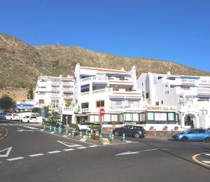 a large white building with cars parked in front of it at Charming studio Los Cristianos Hill heated pool in Los Cristianos