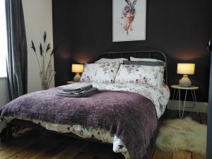 a bedroom with a bed with a purple comforter and two lamps at Aubrey Cottage in Cowbridge