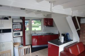 una pequeña cocina con armarios rojos y una silla roja en Huisje 59, en Nieuwe-Niedorp