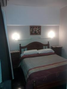 a bedroom with a bed with two lights on the wall at Departamentos del centro in Villa Mercedes