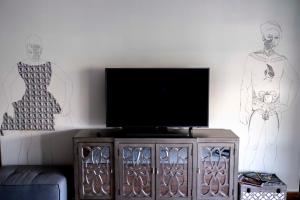 ein Wohnzimmer mit einem TV und Wandzeichnungen in der Unterkunft POP'S APPARTEMENTS RESIDENCE MARISOL au bord de la mer in Le Gosier