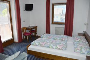 a hotel room with a bed and a table and window at Pension Pichler in Chienes