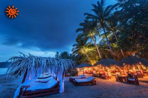 a beach with chairs and umbrellas and the ocean at Locanda Samara Beach in Sámara