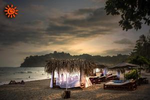 a beach with tables and umbrellas and the ocean at Locanda Samara Beach in Sámara