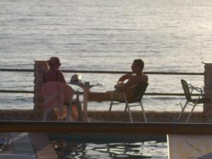 a man and a woman sitting at a table by the water at Agelica Apartments in Kalymnos