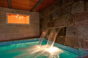 a swimming pool with a waterfall in a stone wall at Parralito by VillaGranCanaria in Ingenio