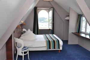 a attic bedroom with a bed and a window at Hôtel des Rochers in Perros-Guirec