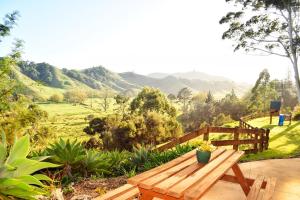 a wooden bench in a garden with mountains in the background at Coastal Chalet Suites Whangaroa in Kaeo