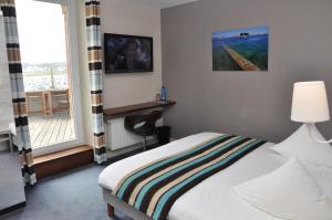 a bedroom with a bed and a window with a balcony at Hôtel des Rochers in Perros-Guirec