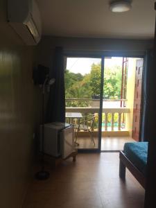 Zimmer mit einem TV und einer Tür zu einem Balkon. in der Unterkunft Cherrys @ Home Too Inland Resort in Panglao