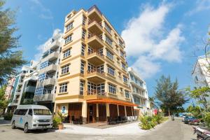 un edificio amarillo con una furgoneta estacionada frente a él en Three Inn, en Hulhumale