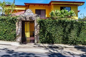a house with a gate in front of a hedge at La Terraza Guest House B&B in Grecia