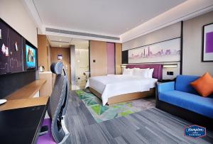 Pokój hotelowy z łóżkiem i niebieskim krzesłem w obiekcie Hampton by Hilton Guangzhou Dongxiaonan w Guangzhou