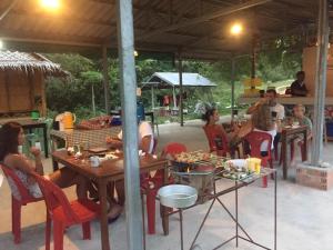 een groep mensen die aan tafel zitten in een openluchtrestaurant bij Koh Phaluai Beach Bangalow in Ban Ko Nok Taphao