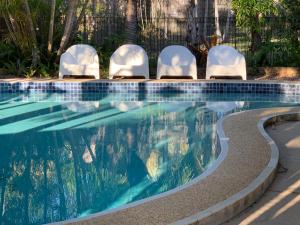 a swimming pool with chairs and a swimming pool at Tin Can Bay Motel in Tin Can Bay