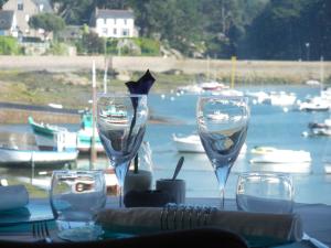 a table with wine glasses on a table with a harbor at Hôtel des Rochers in Perros-Guirec