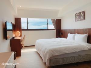 Schlafzimmer mit einem Bett, einem Schreibtisch und einem Fenster in der Unterkunft Seeing Inn in Taitung