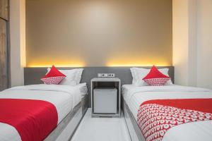 two beds with red pillows in a room at OYO 1487 Residence Khoe in Jakarta