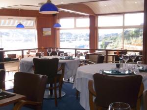 a restaurant with two tables and chairs and windows at Hôtel des Rochers in Perros-Guirec