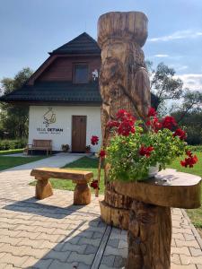 eine hölzerne Statue eines Bären mit einer Bank und Blumen in der Unterkunft Villa Detvan in Stará Lesná