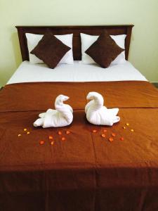 two swans are sitting on a bed with flowers at Madara Hotel in Horana