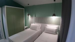 2 camas en una habitación con paredes verdes y 2 luces en Bistrica Hotel, en Sarandë