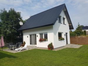 a white house with a black roof and a lawn at Dom pod Orzechem in Świnoujście