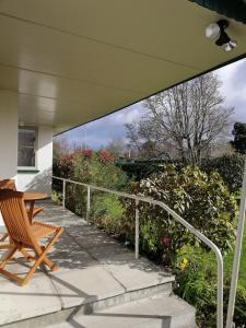 un portico con una sedia, un tavolo e alcuni cespugli di Super Central Cosy Greytown House with Garage a Greytown