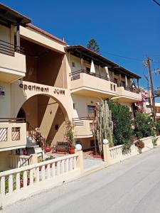 a building with a white fence next to a street at John Apartments in Platanias