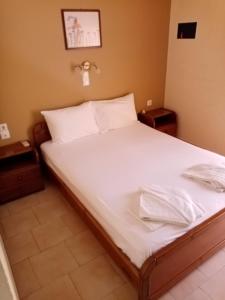 1 cama con sábanas blancas y almohadas en una habitación en John Apartments, en Plataniás