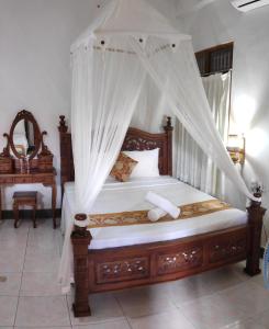 a bedroom with a wooden bed with a canopy at Praety Home Stay in Ubud