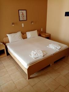 a bedroom with a large bed with white sheets at John Apartments in Platanias