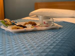 un plato de comida y una taza de café en una cama en Albergo Papillon, en San Polo dʼEnza in Caviano