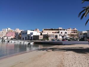 einen Strand mit Gebäuden und Booten im Wasser in der Unterkunft Appartamento Porto Vecchio in Lampedusa