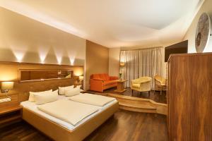 una camera da letto con un letto e un soggiorno di Angerhof Sport- u. Wellnesshotel a Sankt Englmar Altre 51 foto