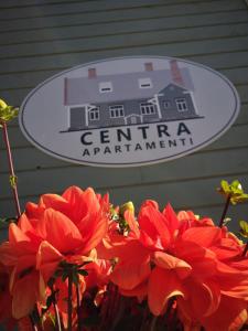 a sign for a centennial apartment with red flowers at Centra apartamenti in Jēkabpils