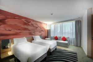 a hotel room with two beds and a couch at Novotel Sharjah Expo Centre in Sharjah