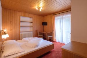 a bedroom with a bed with a table and a window at Gasthof Löwen in Nova Levante