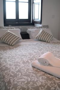 a large bed with pillows and a blanket on it at Quinta dos Capuchos Casa da Adega in Alcobaça