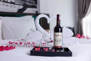 eine Flasche Wein und ein Glas auf dem Bett in der Unterkunft Hanoi Center Silk Lullaby Hotel and Travel in Hanoi