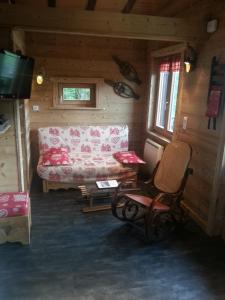 una sala de estar con sofá y sillas en una cabaña en Le Valmandine, en La Bresse