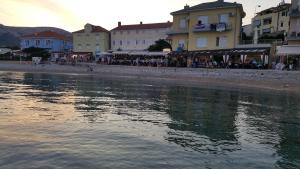 a group of buildings on a beach next to a body of water at Apartments Krstulja in Baška +9 photos