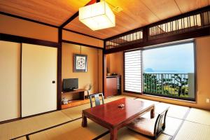 een woonkamer met een tafel en een groot raam bij Hotel Uohan in Karatsu