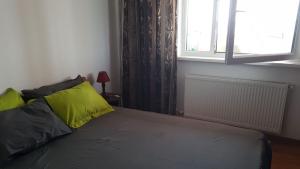 a bedroom with a bed with yellow pillows and a window at Faleza Nord Sea View Apartment in Constanţa