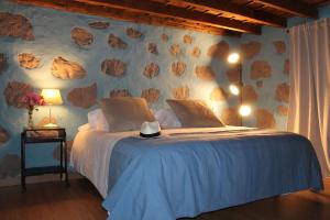 - une chambre avec un lit et un mur en pierre dans l'établissement Casa Fita en El Cubo de La Galga, à Puntallana
