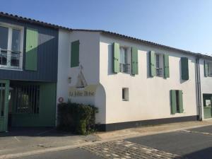 un edificio blanco con persianas verdes en una calle en la jolie brise en Ré dans résidence avec piscine, en La Flotte