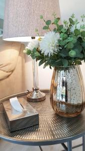 eine Glasvase mit weißen Blumen auf dem Tisch in der Unterkunft Carrington Cottage in Kapstadt