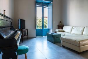 een woonkamer met een piano en een bank bij La terrazza dei Normanni in Aci Castello