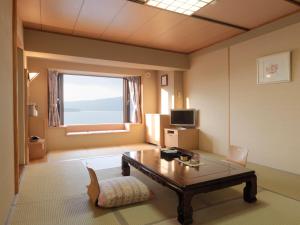 ein Wohnzimmer mit einem Tisch und einem Fenster in der Unterkunft Akan No Mori Tsuruga Resort Hanayuuka in Akankohan