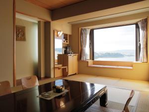 a living room with a table and a large window at Akan No Mori Tsuruga Resort Hanayuuka in Akankohan